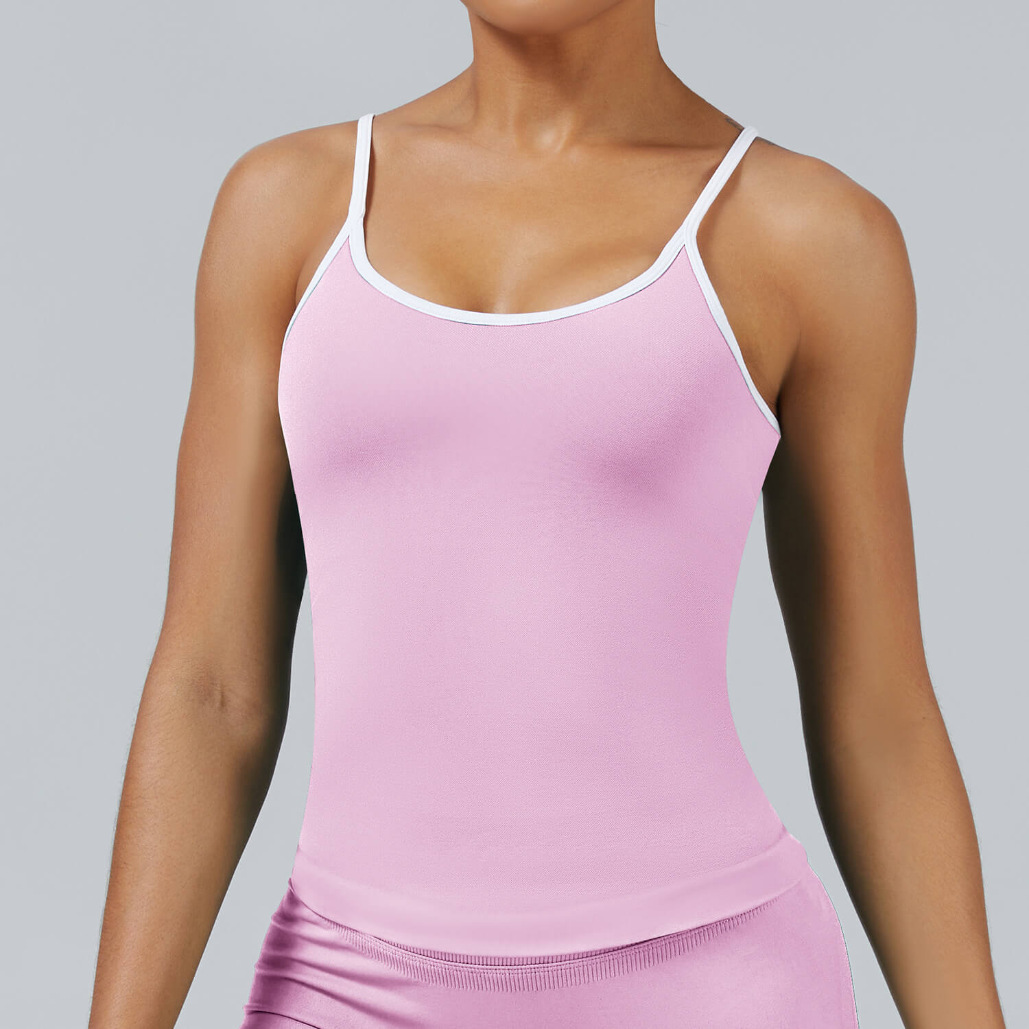 Women's seamless cami tank top in pink with removable pads, featuring white contrast trim and ribbed hem detail for activewear and yoga